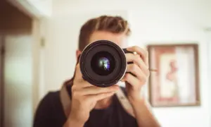 Osoba z aparatem przed twarzą, zastanawia się: canon czy nikon?