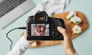 Ręce trzymają lustrzankę, na której ekranie widać zdjęcie jedzenia. Idealna lustrzanka na początek dla każdego fotografa.