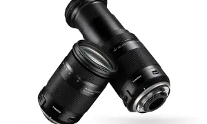 Dwa obiektywy Tamron 18-400 mm, jeden z wysuniętym zoomem, drugi z zasuniętym, unoszą się na białym tle.