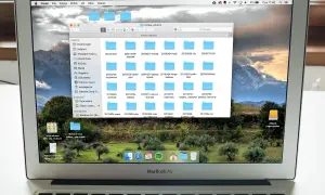 Na ekranie MacBook Air widać okno programu do segregowania zdjęć, z folderami o nazwach dat.