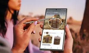 Ręka z rysikiem S Pen używa aparatu cyfrowego Samsung Galaxy do wyszukiwania plecaków podróżnych.