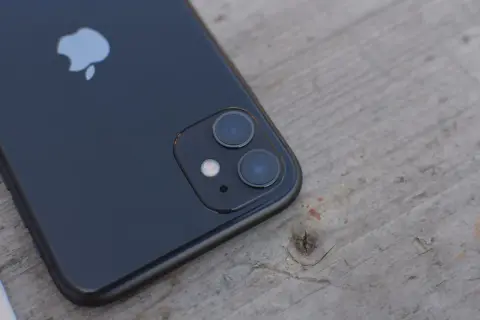 Czarne iPhone'a z podwójnym aparatem na drewnianym tle. Dowiedz się, jak wyłączyć Live Photo.