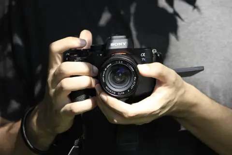 Dłonie trzymające aparat Sony Alpha 7s, gotowe do ustawienia ostrości.
