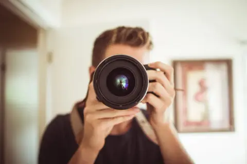 Osoba z aparatem przed twarzą, zastanawia się: canon czy nikon?
