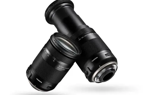 Dwa obiektywy Tamron 18-400 mm, jeden z wysuniętym zoomem, drugi z zasuniętym, unoszą się na białym tle.