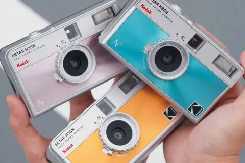 Trzy kolorowe aparaty Kodak Ektar H35N, każdy z innym odcieniem, leżą w dłoni. Dowiedz się, jak działa aparat jednorazowy Kodak.