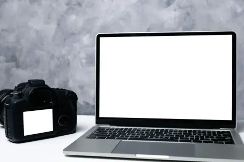 Aparat cyfrowy i laptop obok siebie. Idealne do nauki, jak przenieść zdjęcia z aparatu cyfrowego na telefon.
