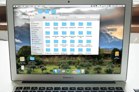 Na ekranie MacBook Air widać okno programu do segregowania zdjęć, z folderami o nazwach dat.