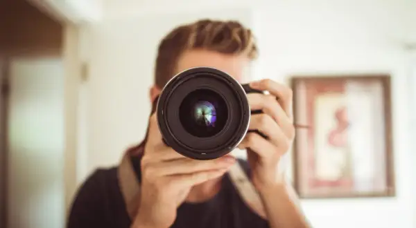 Osoba z aparatem przed twarzą, zastanawia się: canon czy nikon?