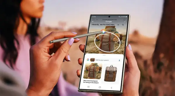 Ręka z rysikiem S Pen używa aparatu cyfrowego Samsung Galaxy do wyszukiwania plecaków podróżnych.