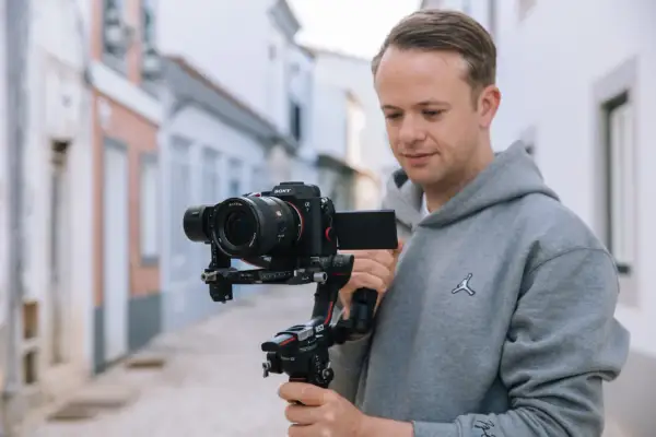 Mężczyzna z kamerą Sony Alpha 7 na stabilizatorze DJI Ronin S2. Zastanawiasz się, który aparat fotograficzny wybrać?