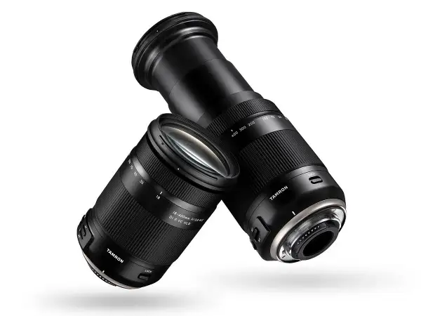 Dwa obiektywy Tamron 18-400 mm, jeden z wysuniętym zoomem, drugi z zasuniętym, unoszą się na białym tle.