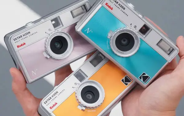 Trzy kolorowe aparaty Kodak Ektar H35N, każdy z innym odcieniem, leżą w dłoni. Dowiedz się, jak działa aparat jednorazowy Kodak.