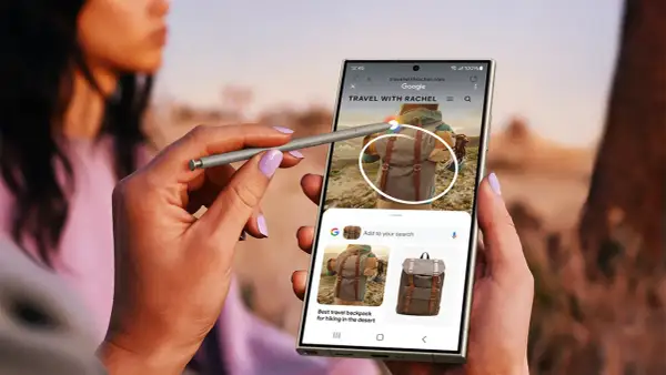 Ręka z rysikiem S Pen używa aparatu cyfrowego Samsung Galaxy do wyszukiwania plecaków podróżnych.